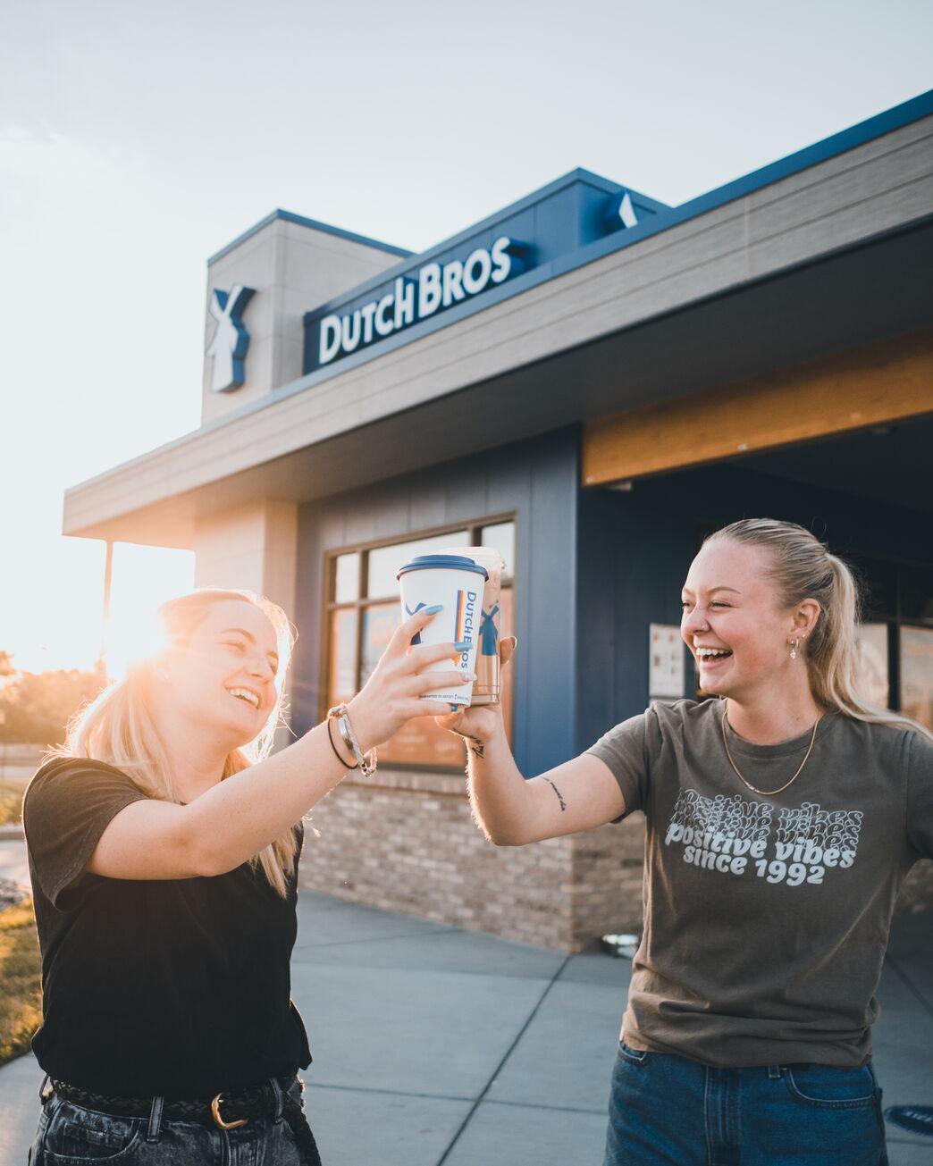 two girls outside of a dutch bros building holding coffee